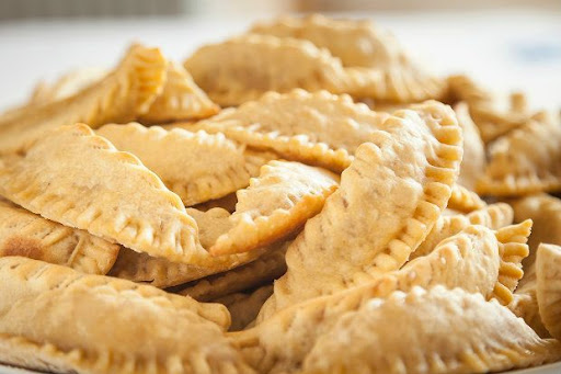 Traditional Greek kaltsounia pastries from Samos filled with ricotta and drizzled with honey and cinnamon