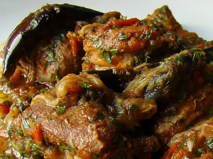 Roasted goat with eggplants in tomato sauce, served in a traditional Greek dish – recipe from Samos