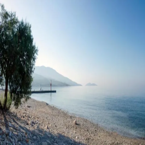 Όρμος Κουμαίικων Σάμου με ψαρόβαρκες, πέτρινα σπίτια και ήρεμη θάλασσα.