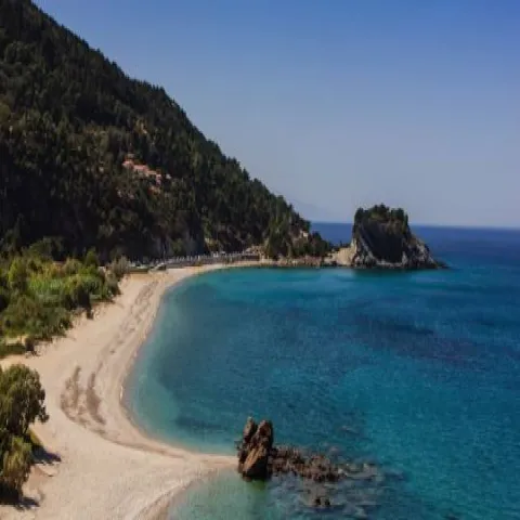 Παραλία Ποτάμι στη Σάμο με λευκά βότσαλα και καταρράκτες στο βάθος.