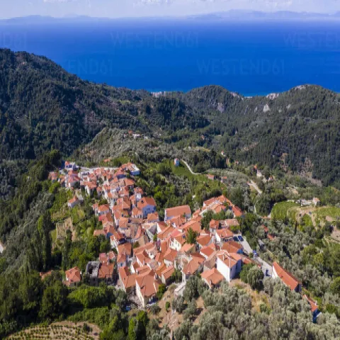 Stenen straatjes en traditionele huizen in Manolates op Samos, omringd door groen.