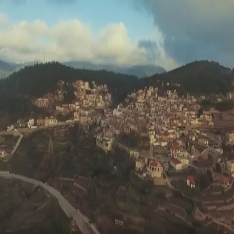 Γενική άποψη του Πλατάνου Σάμου μέσα σε δάσος με φόντο το όρος Καρβούνης.