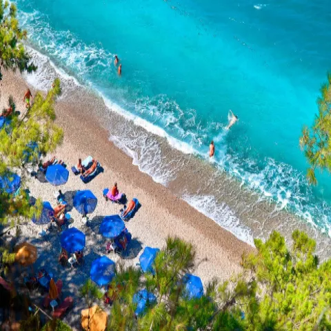 Παραλία Τσαμαδού στη Σάμο με καταγάλανα νερά και βότσαλα μέσα σε καταπράσινο τοπίο